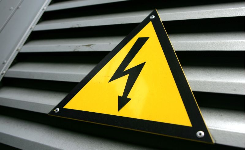 Emaljēta brīdinājuma zīme “Uzmanību! Elektrība” par augsto spriegumu pie transformatora apakšstacijas durvīm.