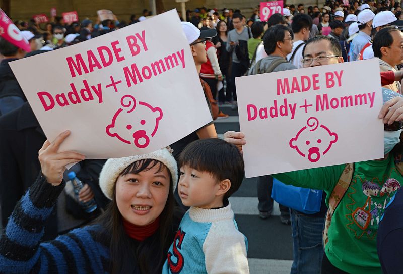 A mother displays a sign with her son during the anti-same sex marriage demonstration in Taipei on November 30, 2013. Opponents and supporters of same-sex marriages took to the streets in Taiwan amid an ongoing debate in parliament over a controversial bill to legalise such unions. AFP PHOTO / Sam Yeh