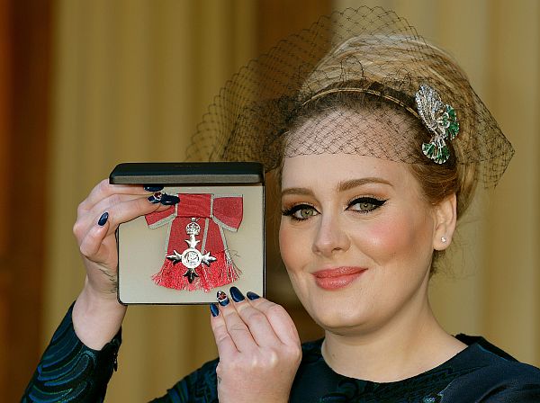 British singer-songwriter Adele Adkins holds her medal after being appointed a Member of the Order of the British Empire (MBE) for services to music presented to her by the Prince Charles, Prince of Wales during an investiture ceremony at Buckingham Palace in London on December 19, 2013. AFP PHOTO / POOL / JOHN STILLWELL