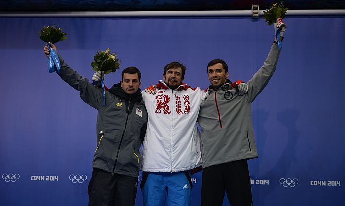 (From L) Latvia’s silver medalist Martins Dukurs, Russia’s gold medalist Alexander Tretiakov, and US bronze medalist Matthew Antoine stand on the podium of the Men’s Skeleton Flower Ceremony at the Sanki Sliding Center in Rosa Khutor during the Sochi Winter Olympics on February 15, 2014. AFP PHOTO / LIONEL BONAVENTURE
