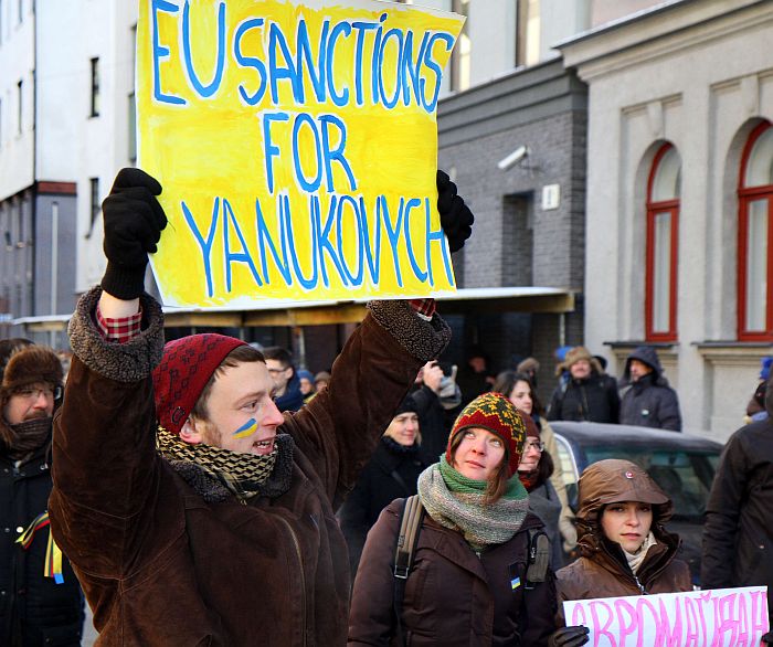A protestor holds a sign reading ” EU sanctions for Yanukovich” during the “Stretch out your hand to Ukraine” demonstration against the escalation of anti-government protests in Ukraine on January 25, 2014 in Vilnius. The protestors built a human chain between the European Commission Representation office in and the Ukraine Embassy in Lithuania. AFP PHOTO / PETRAS MALUKAS