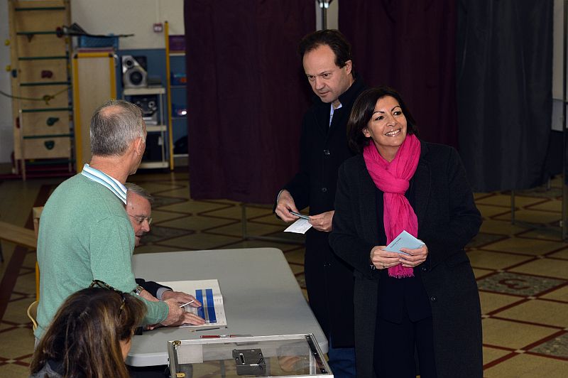 Paris Deputy Mayor and French Socialist party (PS) candidate for the Paris municipal elections, Anne Hidalgo,smiles before casting her ballot in the first round of the French municipal elections on March 23, 2014 at a polling station in Paris, next to her husband Jean-Marc Germain. Sunday’s contest is the first nationwide vote since Socialist leader Francois Hollande was elected as president two years ago. AFP PHOTO / MIGUEL MEDINA