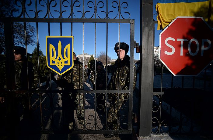 Ukrainian soldiers look out through a gate near a “stop” sign as they wait inside the Sevastopol tactical military brigade base near Belbek in Sevastopol on March 3, 2014. Russian forces have given Ukrainian soldiers an ultimatum to surrender their positions in Crimea or face an assault, a Ukrainian defence ministry spokesman said. “The ultimatum is to recognise the new Crimean authorities, lay down our weapons and leave, or be ready for an assault,” said Vladyslav Seleznyov, the regional ministry spokesman for the Crimea. AFP PHOTO / FILIPPO MONTEFORTE
