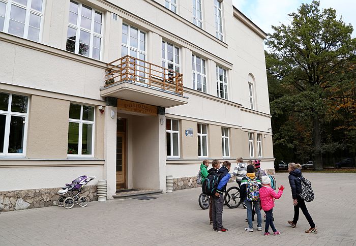 Skolēni pie Pumpuru vidusskolas ēkas, kuras pirmajā stāvā iebrukuši piekaramie griesti.