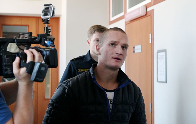 Otrs no aizturētajiem vīriešiem tiek konvojēts pēc Rīgas apgabaltiesas sēdes, kurā aiz slēgtām durvīm noraidīja sūdzību par apcietinājuma atcelšanu, kurš tiek turēts aizdomās par pērn janvārī veikto uzbrukumu bijušajam Satversmes aizsardzības biroja vadītājam Jānim Kažociņam.