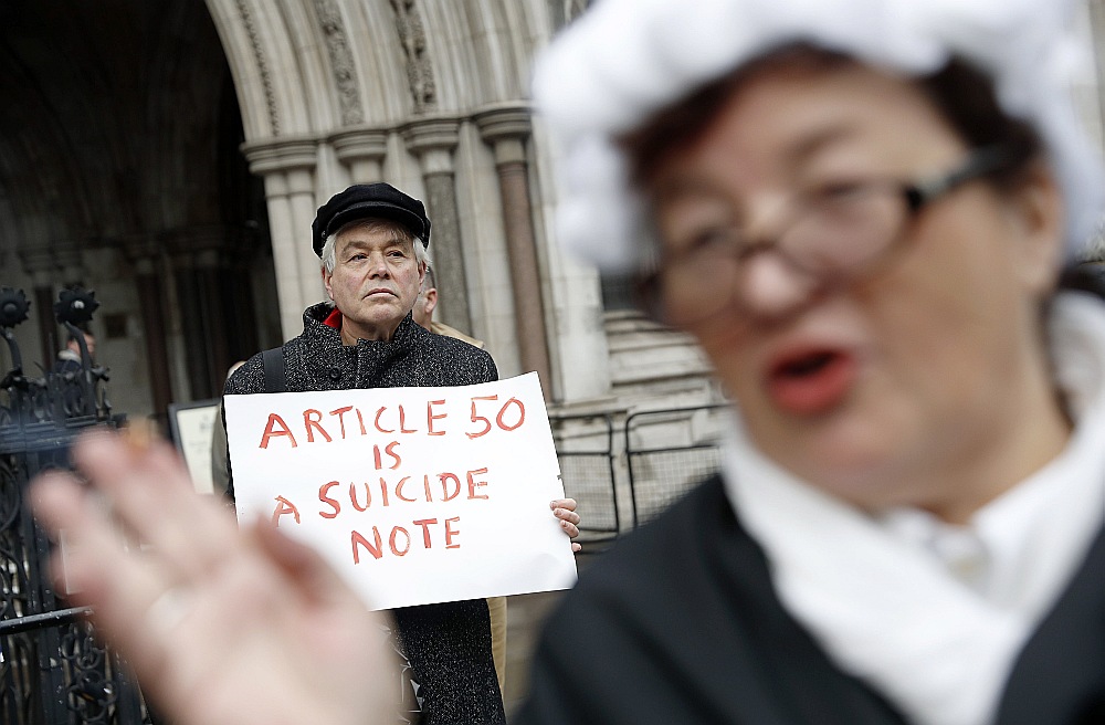 Politiskās cīņas atbalsojas ielās. “Brexit” atbalstītājs no kustības “Iedarbini 50. pantu tūlīt!” ģērbies kā tiesnesis pie Lielbritānijas Augstākās tiesas. Aizmugurē “Brexit” pretinieks ar plakātu “50. pants ir pašnāvības zīme”.