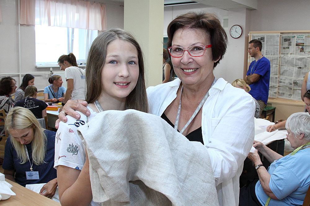 “Man ļoti patīk latviešu valoda!” saka Norvēģijā dzimusī Kate Rastiņa. Kopā ar vecmāmiņu viņa “3×3” saietā mācījās šūt lina kreklu.