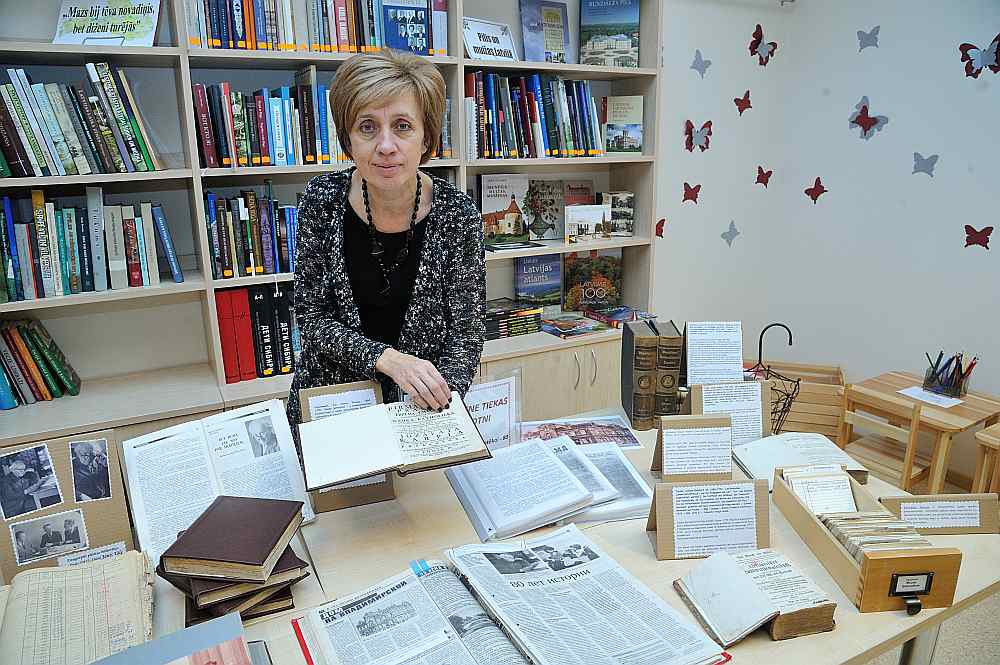 Latgales Centrālās bibliotēkas vadītāja Jeļena Šapkova pie bibliotēkas jubilejai veltītās grāmatu izstādes “Kad pagātne tiekas ar nākotni”.