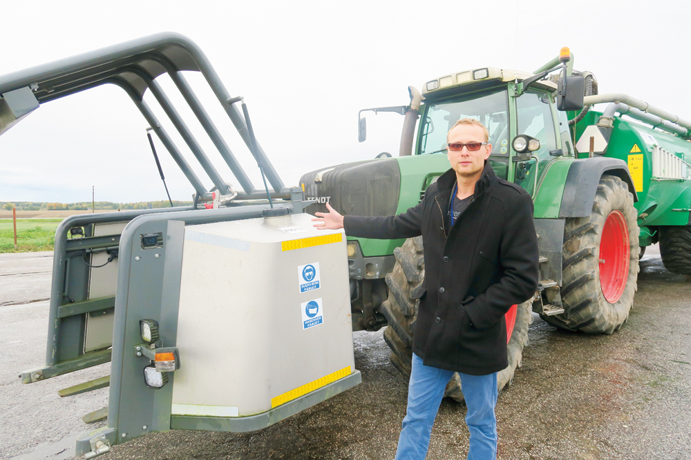 “Lauku Agro” projekt vadītājs Gints Jakubovskis pie sērskābes tvertnes. No tās skābi sūknē uz maisītāju mucas aizmugurē.