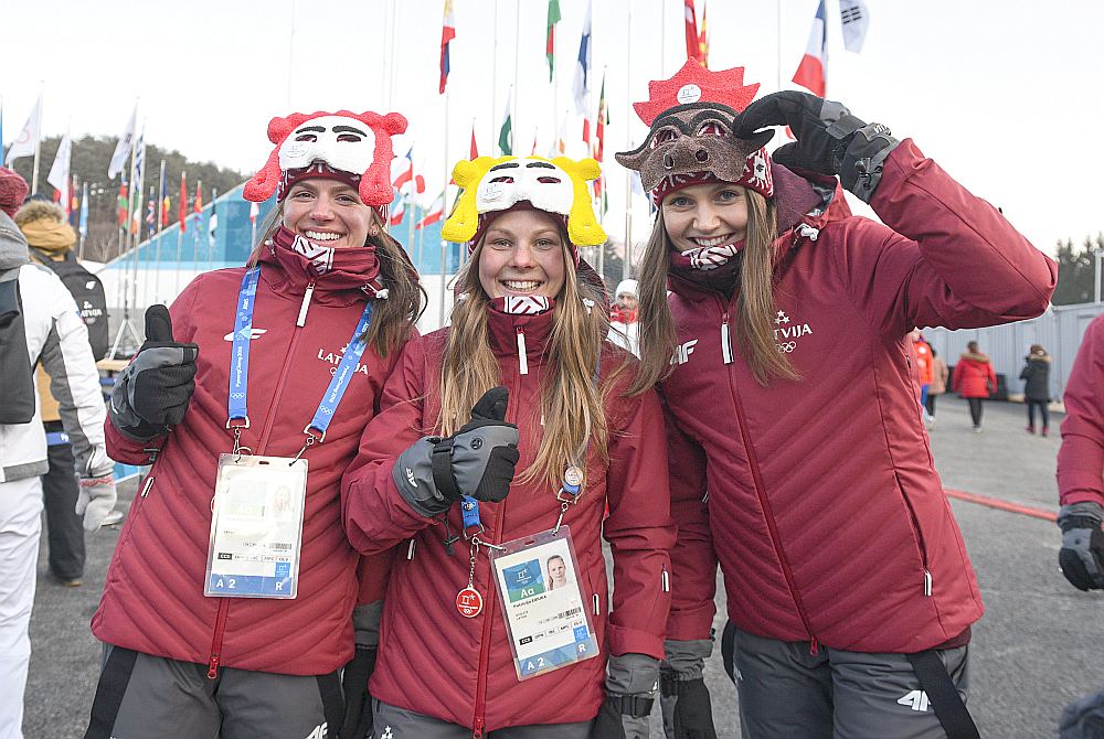 Latvijas kamaniņu sportiste Ulla Zirne (no labās), distanču slēpotājas Patrīcija Eiduka un Inga Paškovska pēc Latvijas karoga pacelšanas ceremonijas olimpiskajā ciematā.