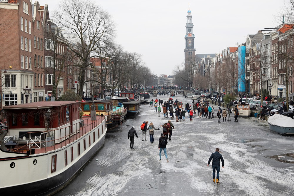 Amsterdamas kanāli aizsaluši, cilvēki tajos slido!