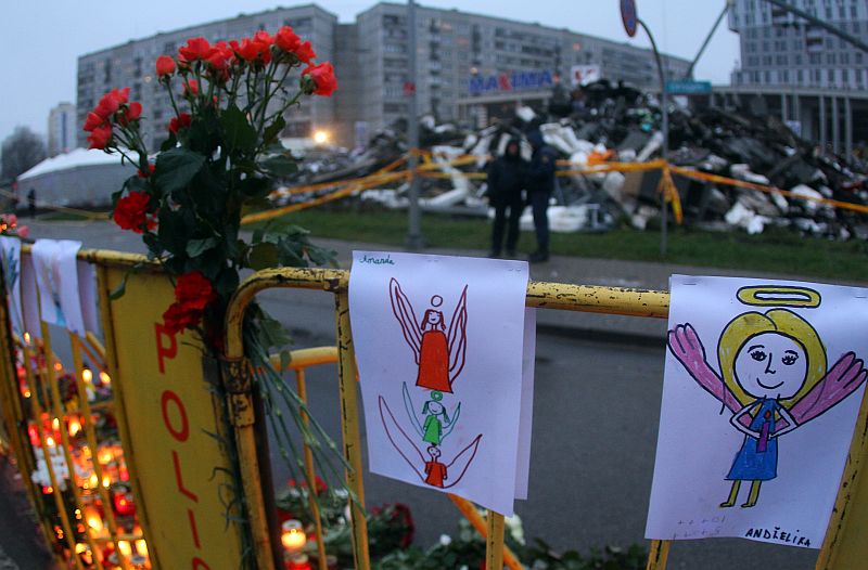 Paintings and flowers are fixed on a fence near the accident site of a collapsed Maxima supermarket in Riga on November 23, 2013, where the roof of the building caved in on shoppers on November 21. Latvia mourned its dead after the supermarket roof collapse left at least 53 dead in Riga and investigators launched a criminal probe into one of Europe’s most deadly building disasters. The small Baltic state of two million began three days of grieving over the Thursday tragedy, Europe’s third worst roof disaster in 30 years. AFP PHOTO / PETRAS MALUKAS