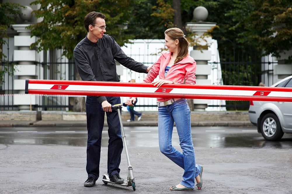 Happy couple with a scooter near the barrier