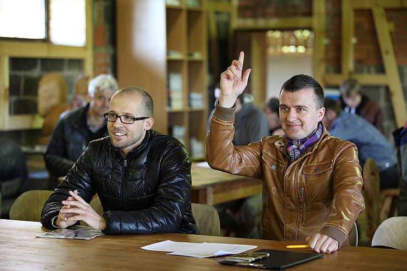 Artis Vidauskis ceļ roku, lai mednieka eksāmena atbildes nodotu vērtēšanai eksaminācijas komisijai. Blakus viņam Aldis Veinbergs gaida sava darba rezultātus. Abi rīdzinieki bija to mednieka kandidātu vidū, kuriem todien “Mārkulīčos” izdevās nokārtot gan teorētisko zināšanu, gan praktisko šaušanas iemaņu pārbaudi.