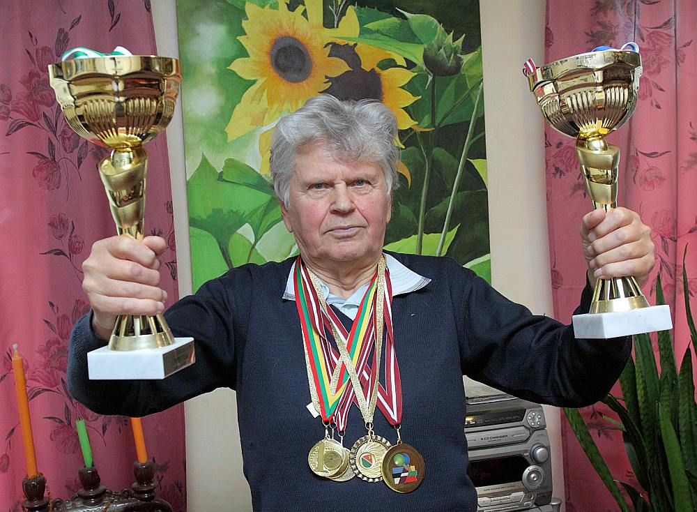 Aivars Kamols ar galda tenisa sacensībās izcīnītajiem kausiem un medaļām.