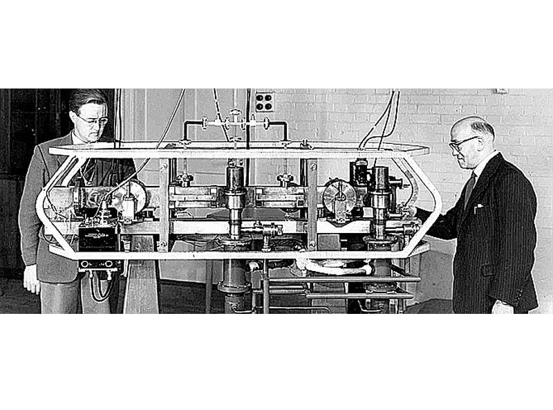 Luijs Esens (pa labi) pie pirmā atompulksteņa.