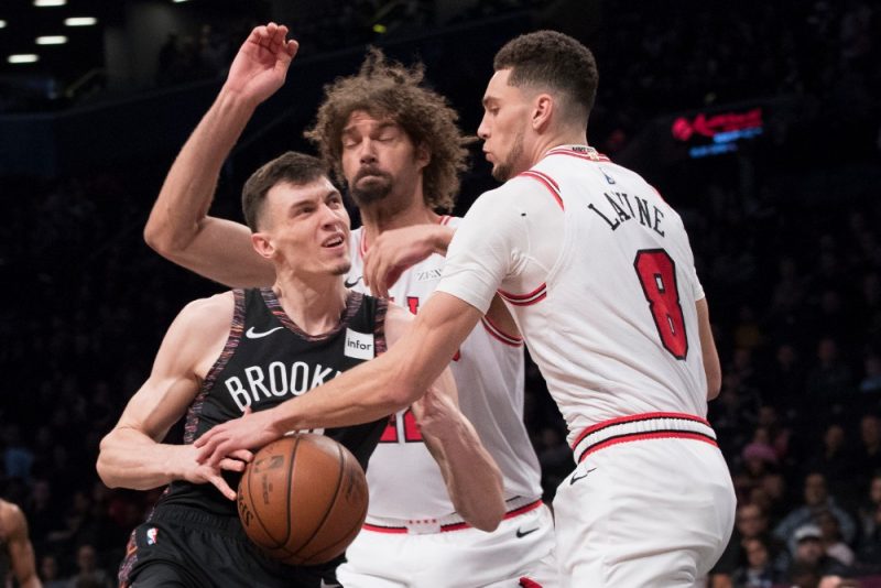Rodions Kurucs (no kreisās) pret Čikāgas “Bulls” spēlētājiem Zeku Levīnu un Robinu Lopesu.