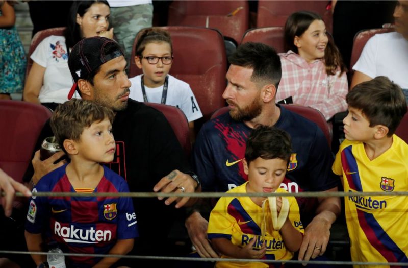 Luiss Svaress (no kreisās) un Lionels Mesi ar dēliem skatās “Barcelona” spēli.
