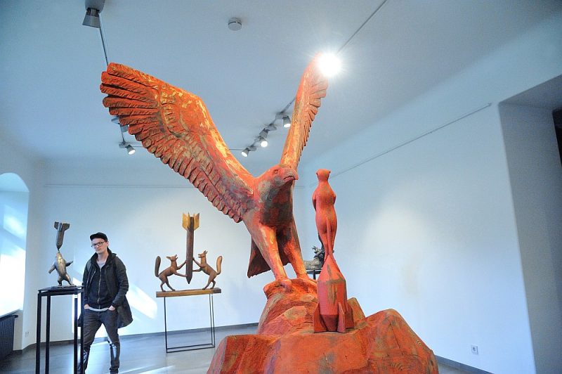 Zvēru dejas ar munīciju ir filigrānas, un to rotaļīgums nav ironisks. Neatbildēts drīzāk paliek jautājums par risinājumu vai mākslas uzdevumu. Priekšplānā: Aigara Bikšes darbs “Putns aprauga surikātu”. Āfrikas dienvidi. 2019. Koks.
