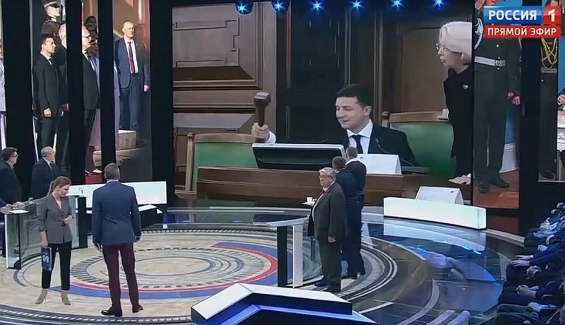 Sarunu šova dalībnieki pievērsušies lielajam ekrānam, lai kopā noskatītos, kā Ukrainas prezidents sit ar āmuriņu.