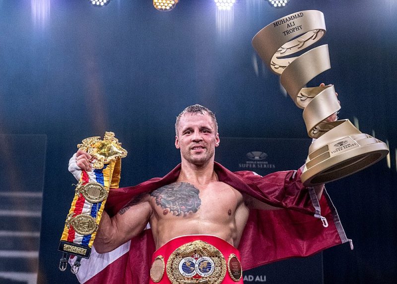 Mairis Briedis ar Muhameda Ali trofeju vienā un žurnāla “The Ring” jostu otrā rokā, bet ap vēderu IBF čempiona josta.