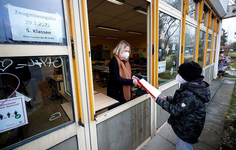 Vācijā skolēni mācās attālināti. Attēlā: janvāra beigās Bonnā skolēns no skolotājas pa klases logu saņem pusgada sertifikātu.